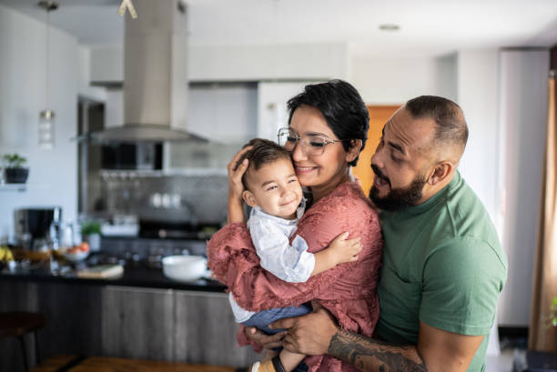 A happy family in their kitchen, with a mother and father embracing their smiling child, highlighting the importance of Miami Mental Health and family well-being.